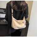 Dettaglio della borsa a mezzaluna bianco crema con trama a grana e ciondolo a pompon - Bianco Sporco