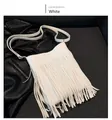 Close-up of white leather crossbody bag with long fringes over a black leather jacket - White