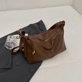 Deep brown lychee grain leather tote bag with gold hardware on a grey suit background - Brown