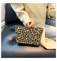 Close-up of stylish leopard print clutch bag held by model with elegant beige trench coat - Tan