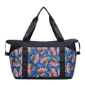 Large travel bag featuring blue and red African wax print with black carry handles - Shell