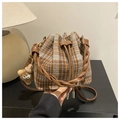 Detail of plaid bucket bag featuring a woven leather handle and furry monster charm - Brown with Pendant