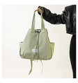 Light green drawstring nylon tote bag with fashion label held by a model in black leather jacket - Light Green
