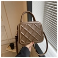 Detail shot of brown quilted crossbody bag with adjustable strap and top handle - Coffee