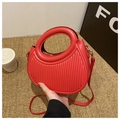 Detail einer roten halbmondförmigen Handtasche mit vertikaler Streifenprägung und Goldreißverschluss - Rot