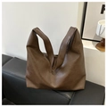 Detalle de bolso tote vintage de cuero marrón oscuro con pliegues naturales en un sofá - café
