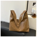 Bolso de hombro de cuero PU marrón sobre un sofá negro en un entorno minimalista - Tostado