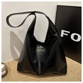 Retro black glossy tote bag with fashion label on woven mat, minimalist shoulder bag style - Black