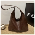 Detail of dark brown glossy leather tote with vintage texture and brand label - Coffee
