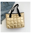 Close-up of golden quilted metallic tote bag with black strap detail and denim accents - Gold
