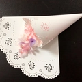 White laser cut wedding confetti cones with rose patterns and scalloped edges on wood table - White