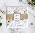 Détail d'une invitation de mariage découpée au laser avec motif floral et ruban doré - Blanc