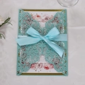 Macro view of laser-cut lace wedding invitation with butterfly patterns and blue silk ribbon - Turquoise Blue
