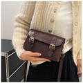 Detail view of a vintage dark brown crossbody bag with gold buckles and adjustable strap - Brown