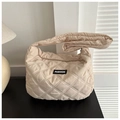 Gros plan du sac matelassé beige avec étiquette FASHION sur une surface noire - Kaki