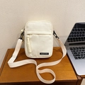 Borsa a tracolla minimalista in tela crema per cellulare su un tavolo di legno - Bianco