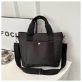 Detail of minimalist black nylon tote bag showing front pocket with silver metal snap button - Black