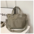 Detail of khaki nylon tote bag featuring front snap pocket and wide adjustable strap - Light Green
