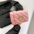 Roze gewatteerde crossbodytas met hartsluiting en kettingriem op zwarte lederen achtergrond - Roze