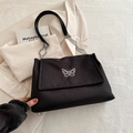Borsa tote nera in tela con ricamo farfalla e catena argentata sopra un blazer - Nero