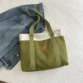 Green and off-white canvas tote bag with leather fashion tag on denim background - Green