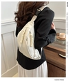 Close-up of minimalist off-white crossbody chest bag with double zippers and woven pullers - White