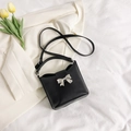 Elegante bolso tipo cubo negro con lazo de mariposa plateado en un ambiente de moda - Negro