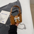 Caramel mini bow handbag with silver buckle and chain strap in a stylish setting - Brown