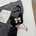 Mini black bow handbag with silver chain strap shown in a minimalist fashion hand-held view - Black