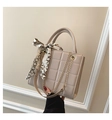 Detailed macro view of beige quilted handbag featuring luxury silk scarf and chain strap - Khaki