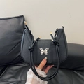 Minimalist black crescent shoulder bag with silver butterfly accent and knotted rope strap - Black