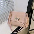 Pink shoulder bag with silver bow buckle and chain strap in soft natural light - Pink