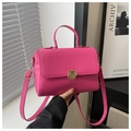 Détail de la texture crocodile rose vif sur un sac à main carré chic avec fermoir doré - rose vif