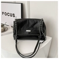 Detail of black glossy leather chain bag featuring silver metal brand plaque and dual straps - Black