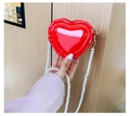 Detalle del bolso rojo en forma de corazón de charol con elegante correa de perlas - Rojo