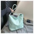 Detailed shot of mint green nylon tote bag with embroidery held over a denim jacket - Teal