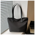 Vista detallada del bolso tote de nailon negro con correas largas sobre un escritorio - Negro