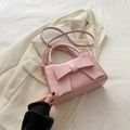 Pink crossbody bag with large bow detail and elegant shoulder strap on beige suit - Pink