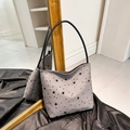 Graue Canvas-Schultertasche mit schwarzen Sternen und Lederriemen auf einer Lederjacke - Stern