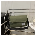Close-up of military green canvas messenger bag showing stitching and brand label detail - Green