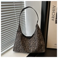 Detail van luipaardprint hobo-tas met slanke zwarte riem op een minimalistische vensterbank - Tan