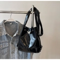 Détail du sac seau noir brillant avec breloque papillon argentée sur un cintre - Noir