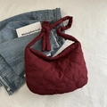 Chic burgundy tote bag with heart quilting and knotted strap on casual background - Red