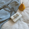 Witte mini tas met zilveren metalen strik en lange kettingriem op grijze stof - Broken Wit