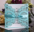 Close-up of laser-cut wedding invitation with blue lace patterns and a satin ribbon bow - Tiffany Blue