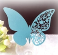 Détail d'un marque-place papillon ajouré bleu clair sur le bord d'un verre de mariage - Bleu Tiffany