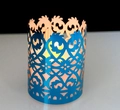 Close-up of blue hollow candle holder with laser-cut floral patterns and warm LED light - Reflective Blue