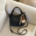Detail of black pebbled leather hobo bag with colorful charms on a soft beige sofa - Black (With Pendant)