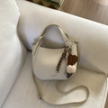 Detail einer cremeweißen Hobo-Tasche mit Litschis-Lederstruktur und modischen Anhängern - Weiß (mit Anhänger)