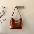 Detalle de bolso bajo el brazo de cuero marrón vintage con cierre giratorio metálico - Rojo Marrón